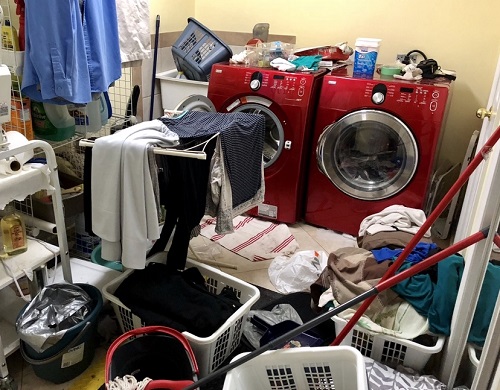 Laundry room with clothes, baskets, cleaning supplies everywhere