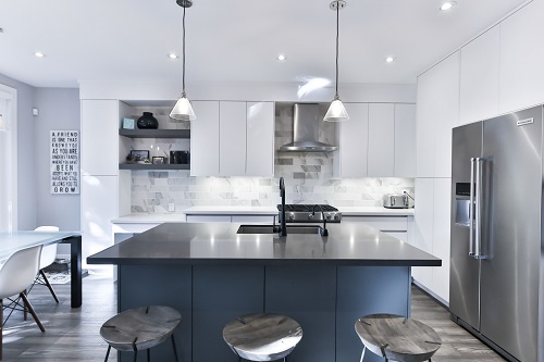 Modern kitchen with white cabinet, stainless steel appliances, island with black countertop and blue base.