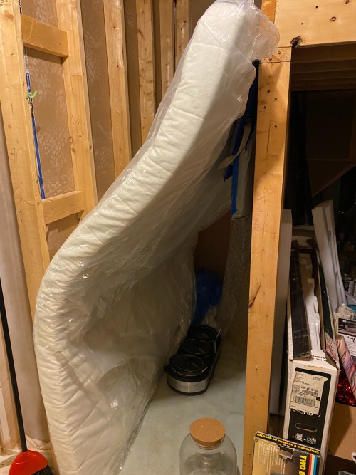 a futon is stored in a narrow space in the basement