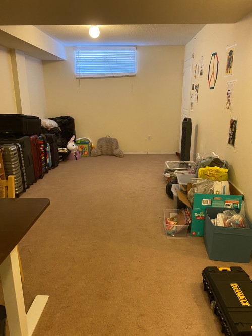 suitcases and a few boxes are stacked along the walls of the basement living space