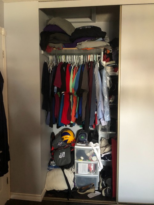 closet with sliding door filled with clothes, shoes and sport equipment