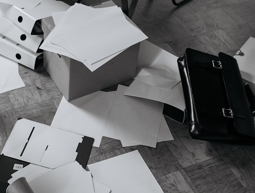 Files, papers and briefcases strewn all over the desk, filing cabinet and floor