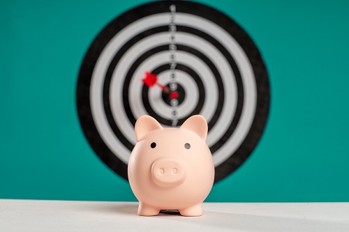 a pink piggy bank in front of a bullseye