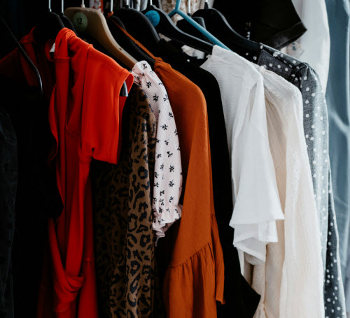 Various clothing pieces in different colours on hangers.