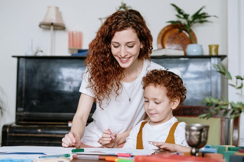 mother and child drawing on paper, sitting in front of the piano