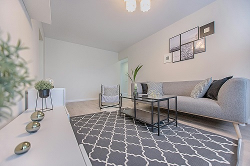 Grey living room - couch with glass coffee table and minimal décor pieces.