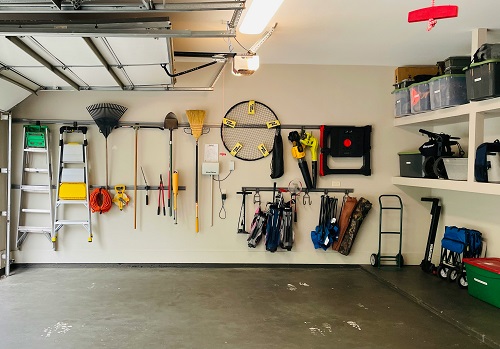 Interior view of an organized garage with items neatly hung on the wall and bins and boxes on shelves.