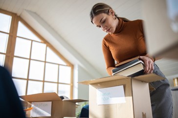 A woman standing in a room putting books into a box