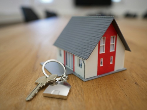 A model house sitting on a table with a set of keys beside it